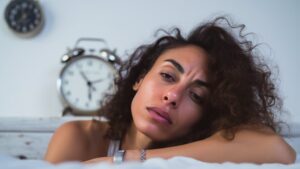 Dormir ocho horas por noche suele considerarse la fórmula básica para sentirse descansado. Sin embargo, muchas personas experimentan una realidad desconcertante: se acuestan a horario, cumplen con las recomendaciones sobre la cantidad de horas necesarias y, aun así, persiste el cansancio Qué es el método 30-30-30, el plan alimentario que ayuda a mantener la masa muscular y la salud intestinal Te puede interesar: Qué es el método 30-30-30, el plan alimentario que ayuda a mantener la masa muscular y la salud intestinal Este fenómeno tiene múltiples explicaciones que van más allá de la duración del sueño y remiten, fundamentalmente, a su calidad y a una serie de condiciones médicas, ambientales, hormonales y conductuales. Una de las razones más frecuentes por las que alguien puede sentirse fatigado tras una noche de sueño aparentemente adecuada es la presencia de trastornos del sueño. El superalimento que los padres deberían ofrecer más a sus hijos, según una pediatra de Harvard Te puede interesar: El superalimento que los padres deberían ofrecer más a sus hijos, según una pediatra de Harvard La apnea del sueño, por ejemplo, interrumpe la respiración de forma repetida durante la noche y genera microdespertares que muchas veces no son conscientes, pero que impiden alcanzar un descanso reparador. La apnea interrumpe la respiración La apnea interrumpe la respiración durante la noche y deteriora la capacidad del cuerpo para recuperarse (Imagen ilustrativa Infobae) La Clínica Cleveland advierte que este tipo de interrupciones pueden producir una fatiga persistente durante el día, a pesar de haber dormido la cantidad de horas recomendadas. Esta situación se traduce, para decirlo de forma sencilla, en la conocida somnolencia diurna. El indicador silencioso, reconocido como un marcador de la salud humana, que podría ser la clave para vivir hasta los 100 años Te puede interesar: El indicador silencioso, reconocido como un marcador de la salud humana, que podría ser la clave para vivir hasta los 100 años Otro trastorno frecuente es el síndrome de piernas inquietas, también conocido como enfermedad de Willis-Ekbom, que se caracteriza por una necesidad imperiosa de mover las piernas, generalmente acompañada de sensaciones incómodas. Según la Clínica Mayo, esta molestia suele presentarse por la tarde o noche, especialmente en reposo, y el movimiento brinda alivio temporal. Asimismo, puede manifestarse a cualquier edad y tiende a empeorar con el tiempo. Además, existen condiciones como la narcolepsia, la hipersomnia y el insomnio, que contribuyen al agotamiento diurno por diversas vías, ya sea por una somnolencia excesiva durante el día o por la imposibilidad de sostener un ciclo de sueño normal. La fatiga constante puede ser La fatiga constante puede ser síntoma de alteraciones hormonales, neurológicas o metabólicas que afectan la recuperación del organismo (Imagen ilustrativa Infobae) Las alteraciones hormonales pueden afectar profundamente el descanso nocturno, generando dificultad para iniciar o mantener el sueño. Según el Instituto Europeo del Sueño, distintas sustancias reguladoras del cuerpo —como el cortisol, la melatonina, la insulina y las hormonas sexuales— intervienen en funciones clave vinculadas al ritmo biológico, la temperatura corporal, el apetito o la respuesta al estrés. Cuando estos sistemas se desequilibran, pueden surgir trastornos como despertares frecuentes, insomnio o una sensación de descanso insuficiente Entre las condiciones más asociadas a este tipo de disfunciones figuran el hipotiroidismo, el síndrome de ovario poliquístico y los cambios hormonales del climaterio. La caída de estrógenos y progesterona en las mujeres —propia de la menopausia— puede provocar sofocos, irritabilidad y sueño fragmentado. En ambos sexos, una baja de testosterona influye sobre la profundidad del descanso. Además, la relación entre insulina y sueño genera un ciclo perjudicial: la falta de descanso puede elevar los niveles de azúcar en sangre, lo que a su vez desregula el apetito y agrava el insomnio. La Clínica Cleveland también advierte que los trastornos tiroideos, especialmente el hipotiroidismo, pueden ralentizar el metabolismo y causar fatiga persistente. Durante el embarazo, sobre todo en el tercer trimestre, es común que el sueño se vea interrumpido por factores hormonales y físicos: aumento de la necesidad de orinar, reflujo, ronquidos o síndrome de piernas inquietas. Para mejorar la calidad del descanso en esta etapa, se recomienda acostarse siempre a la misma hora, evitar comidas pesadas por la noche, moderar el consumo de líquidos y adoptar posturas cómodas para dormir, preferentemente de lado. Ante síntomas persistentes o señales de desequilibrio hormonal, es fundamental consultar con un profesional especializado. Beber alcohol antes de acostarse Beber alcohol antes de acostarse altera las fases internas del ciclo nocturno y reduce la sensación de recuperación al despertar (Imagen Ilustrativa Infobae) La alimentación y el consumo de alcohol también desempeñan un papel relevante. La doctora Marri Horvat, especialista en trastornos del sueño consultada por la Clínica Cleveland, remarca que ingerir una comida abundante o beber alcohol en las horas previas a dormir puede deteriorar la calidad del sueño. Aunque el alcohol pueda inducir el sueño inicialmente, fragmenta las fases de descanso y altera la proporción de sueño profundo y REM, dos etapas fundamentales para la restauración física y mental. Horvart también afirma que estos efectos pueden hacer que una persona se despierte con la sensación de no haber descansado, incluso si ha dormido ocho o más horas. El entorno también puede ser determinante. La presencia de ruidos, luces intensas o una temperatura inadecuada en la habitación son factores que interrumpen el descanso de forma sutil pero constante. La exposición a la luz La exposición a la luz durante la noche interfiere en los ritmos biológicos y deteriora los procesos de recuperación del cuerpo (Imagen Ilustrativa Infobae) Sobre este punto, la doctora Horvat insiste en la necesidad de contar con un espacio oscuro, fresco y silencioso para garantizar un descanso efectivo. Otra causa médica que puede explicar la fatiga persistente es la anemia. Ella explica que la deficiencia de hierro impide que el cuerpo transporte adecuadamente el oxígeno a los tejidos, lo que produce una sensación de agotamiento continuo. Aunque la persona duerma las horas recomendadas, los bajos niveles de hierro pueden impedir una adecuada recuperación energética. Entre los síntomas que acompañan esta condición se encuentran la palidez, los mareos, la falta de aire y, en algunos casos, una sensación de latido fuerte en los oídos. La sensación de fatiga al La sensación de fatiga al despertar puede estar vinculada a trastornos clínicos que alteran funciones esenciales del organismo, aun en ausencia de otros síntomas (Imagen Ilustrativa Infobae) Más allá de estas causas clínicas, también existe una dimensión fisiológica del descanso que puede explicar la fatiga. Según Harvard Health, tanto dormir menos de lo necesario como dormir en exceso puede provocar una mayor percepción de cansancio. Las alteraciones del patrón de sueño, incluso durante los fines de semana, vacaciones o feriados, pueden alterar los ritmos internos del cuerpo y generar una sensación de letargo. La estructura del sueño también resulta crucial. Dormir ocho horas no garantiza haber alcanzado la proporción adecuada de sueño profundo y sueño REM, que son las fases que permiten la recuperación del cuerpo y del sistema nervioso.